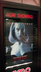 A photograph of a movie poster, a blonde with a seductive look is gazing directly.